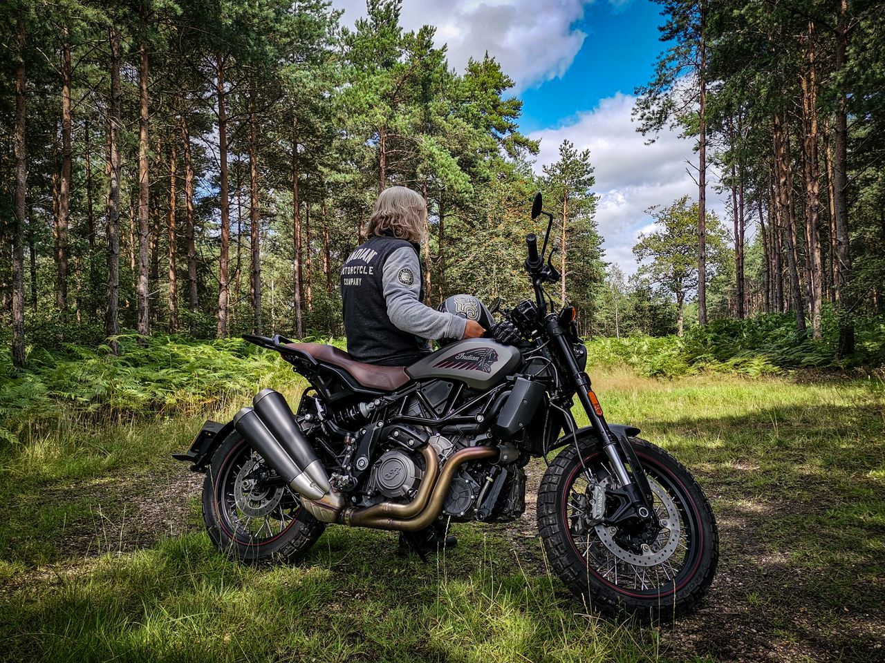 services-img Biker on a motorcycle in a lush forest, surrounded by tall trees.