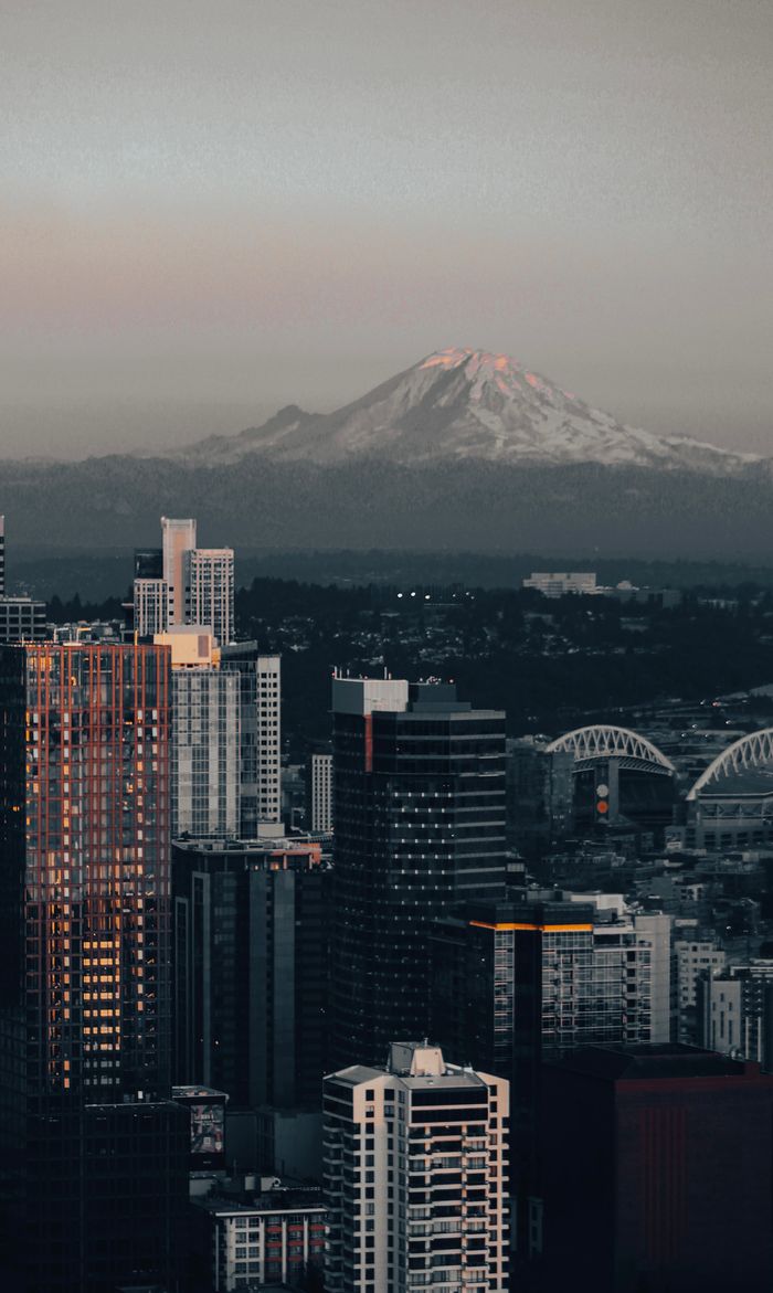 our-experience A scenic view of Seattle's skyline with Mount Rainier in the background at dusk.