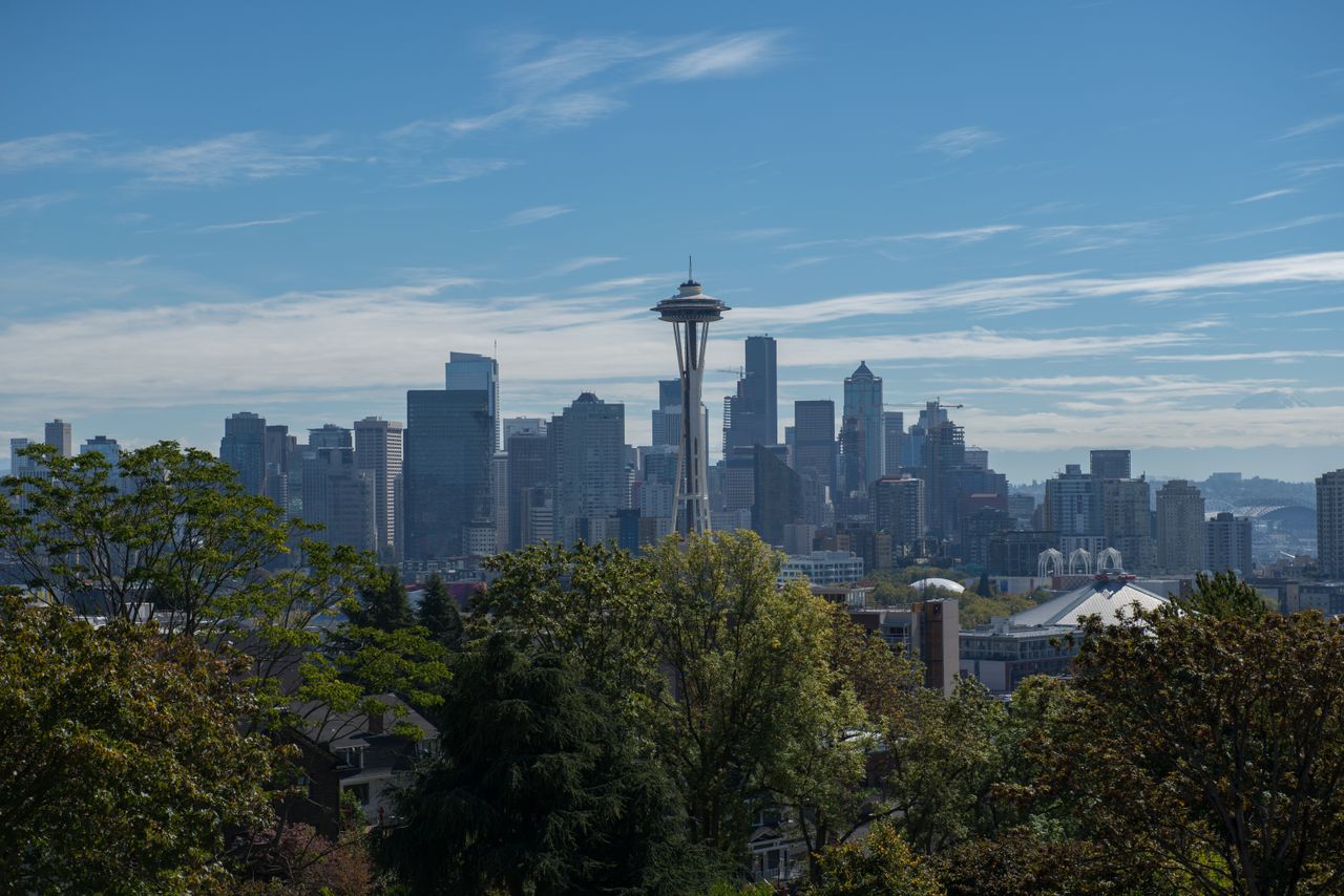 about-img Panoramic view of Seattle with the iconic Space Needle under a clear blue sky.