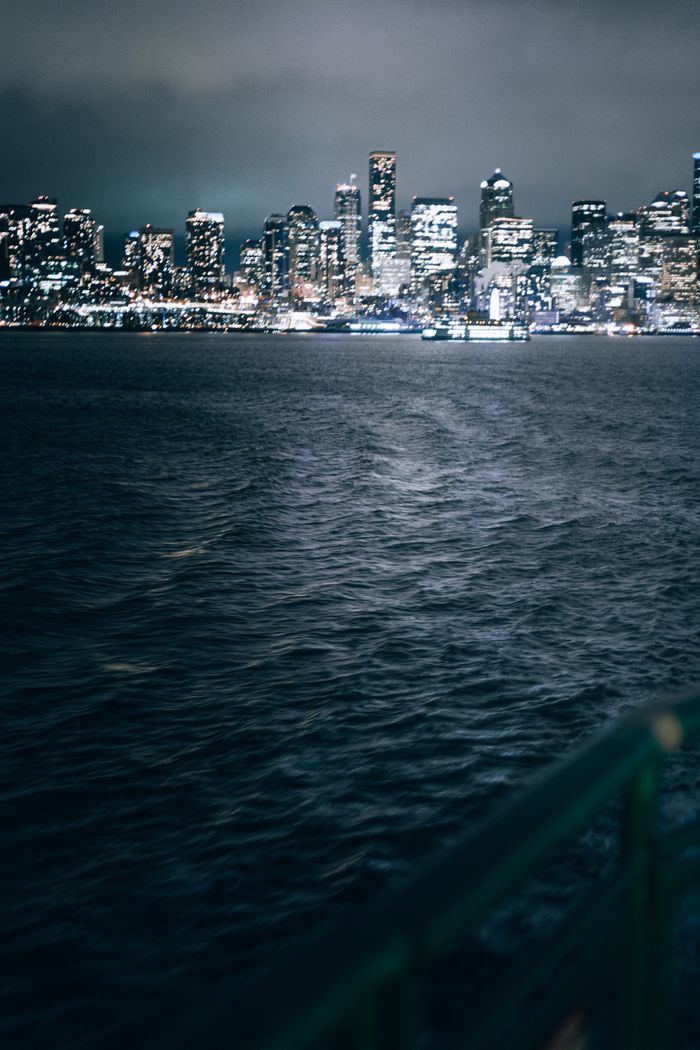 ours-journey Moody view of the Seattle skyline at night from the waterfront, capturing urban lights.