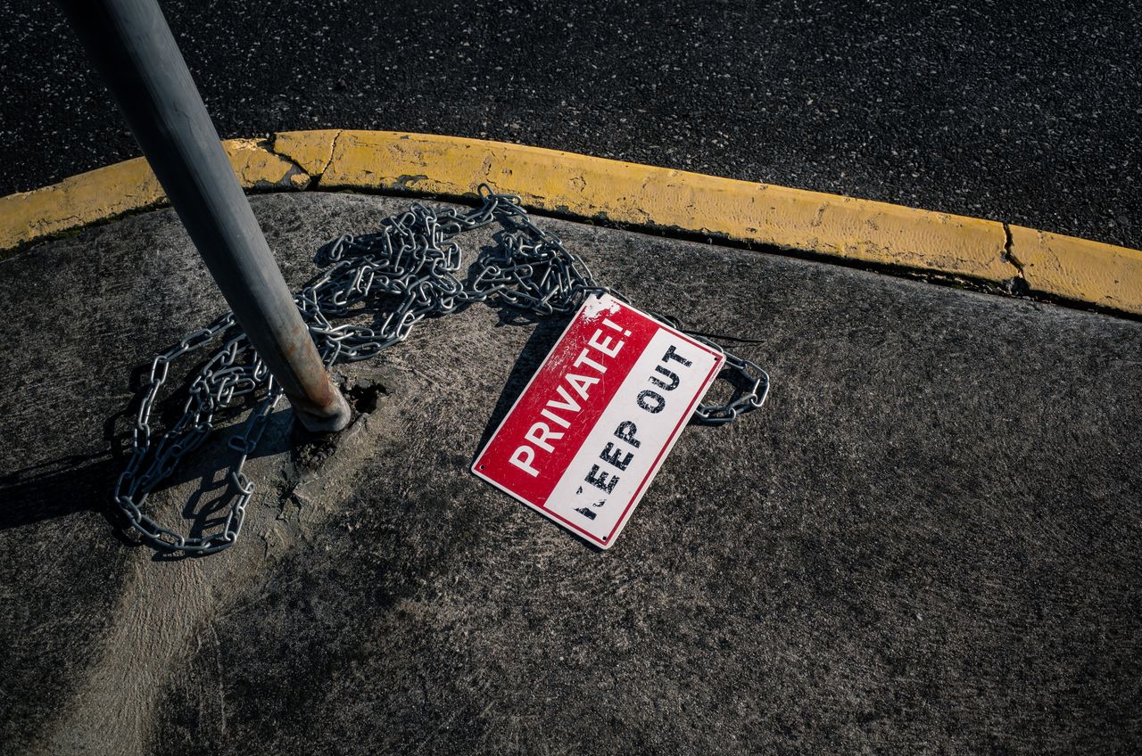 services-02 A chained 'Private Keep Out' sign lies on an urban sidewalk, emphasizing security.